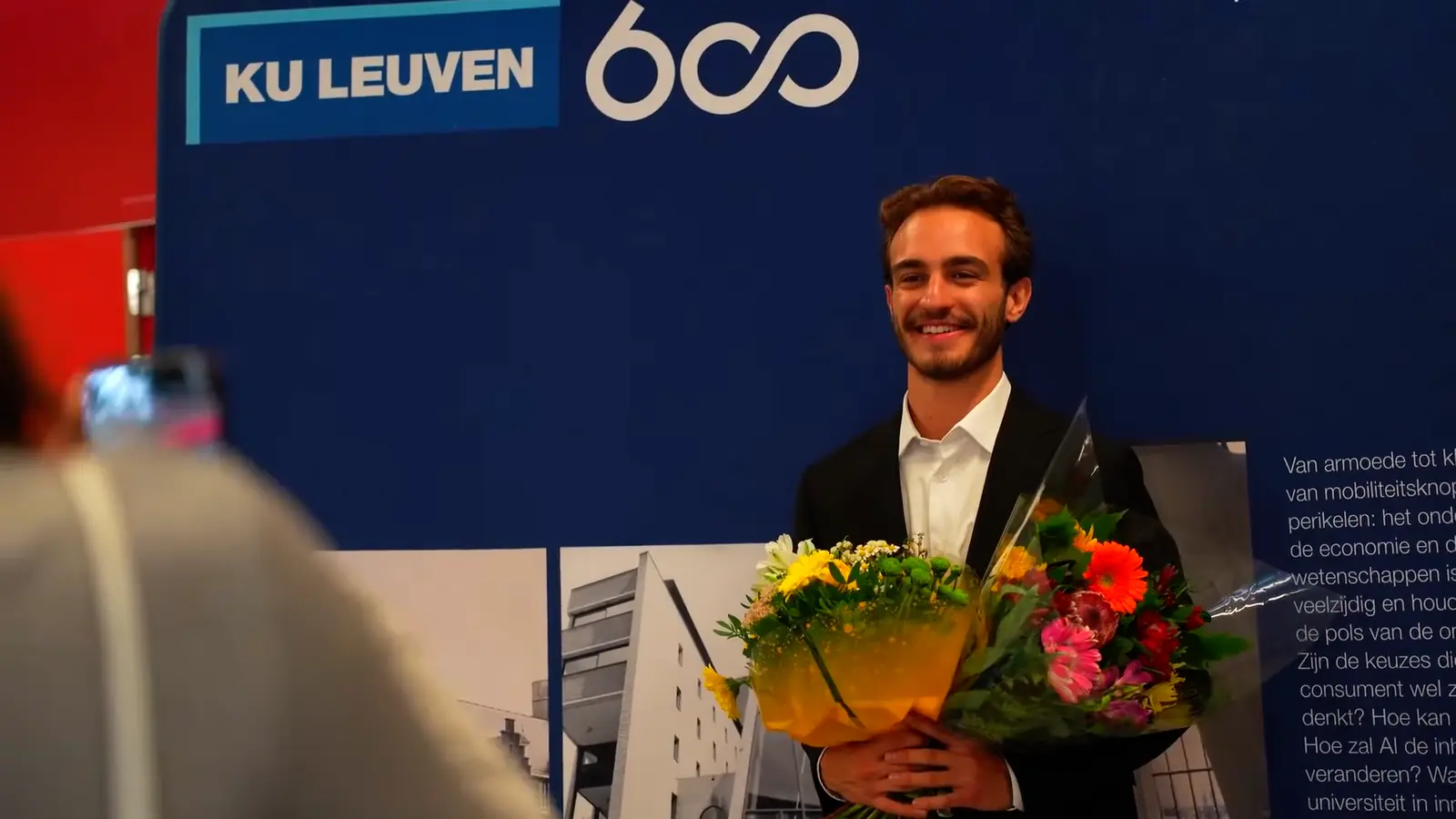 A graduate smiling with flowers after the Brussels ceremony.