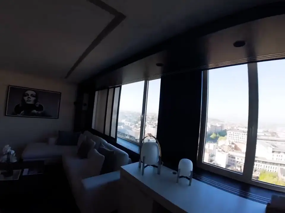 The lounge of a suite at The Hotel, Brussels, with tall windows over the city, on an FPV flythrough.